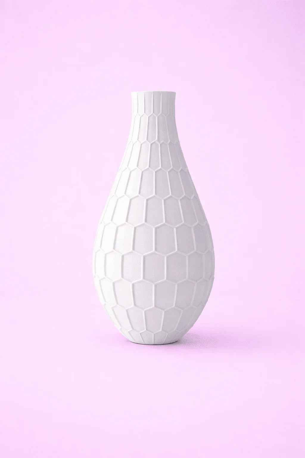 Jarrón blanco de textura geométrica sobre fondo rosa, diseño decorativo moderno