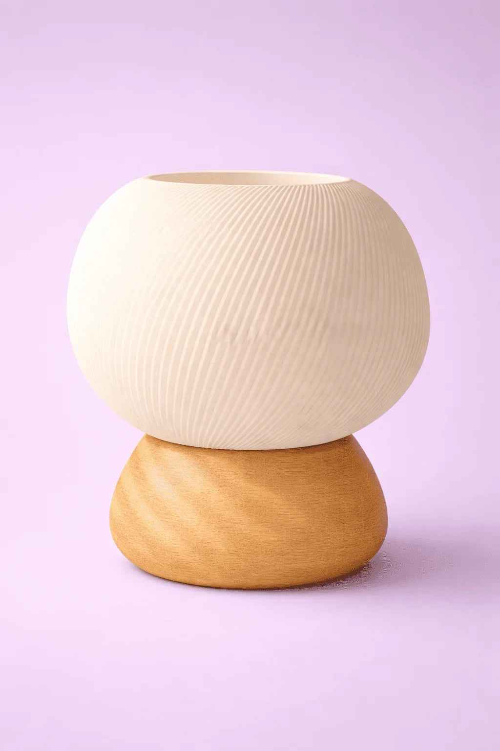 Jarrón decorativo moderno de cerámica y madera sobre fondo lila, diseño minimalista.