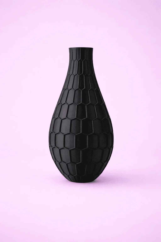 Jarrón negro 3D con diseño hexagonal sobre fondo rosa, decoración moderna.