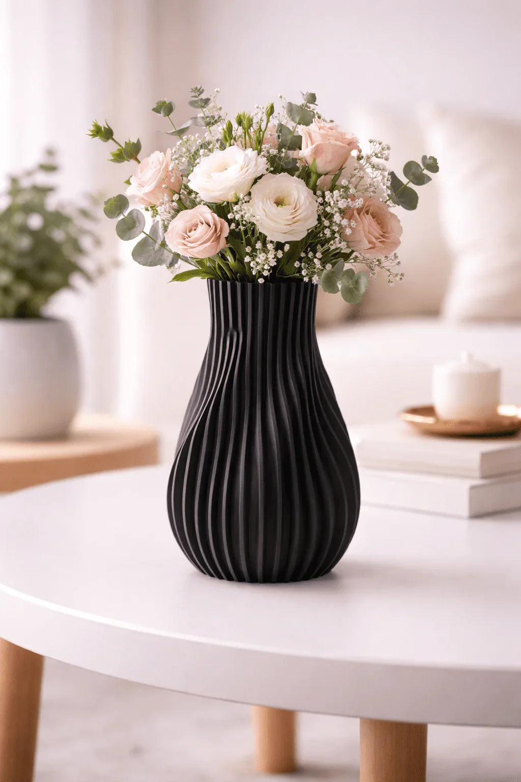 Jarrón negro moderno con relieve y flores sobre mesa blanca en sala minimalista