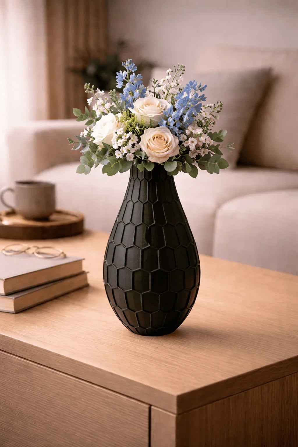 Jarrón negro con textura hexagonal y flores frescas sobre mesa de sala moderna