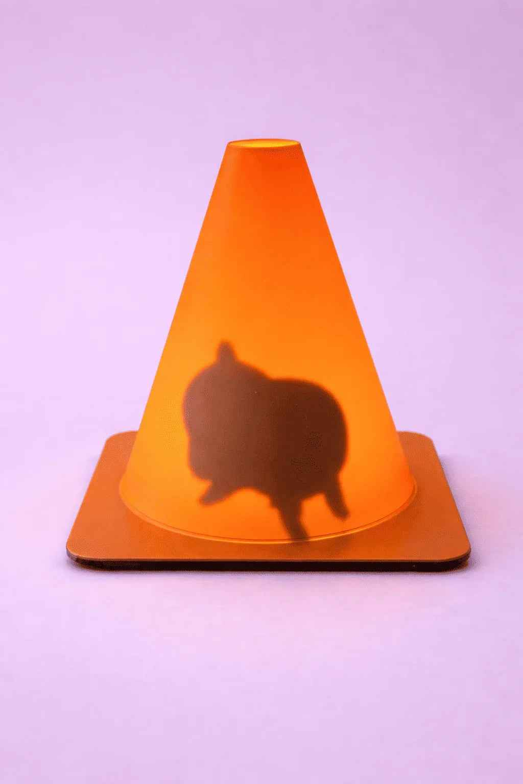 Cono naranja con sombra de animal pequeño sobre fondo lila, decoración creativa.