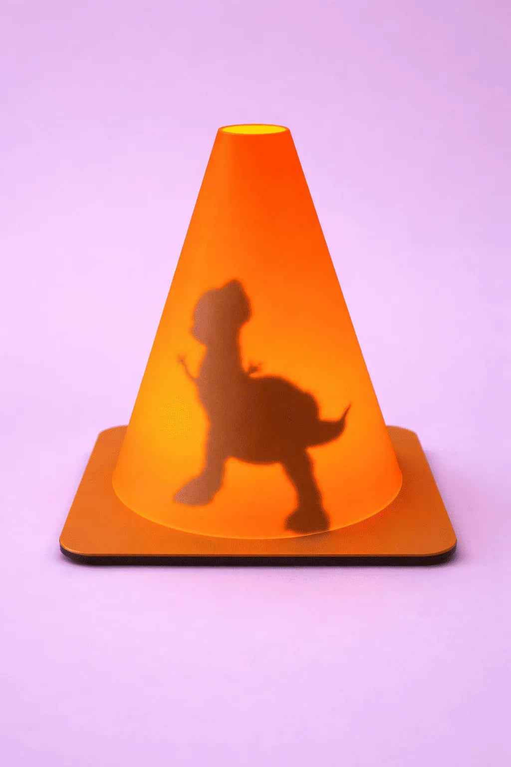 Cono naranja con sombra de dinosaurio sobre fondo lila, decoración creativa y llamativa.