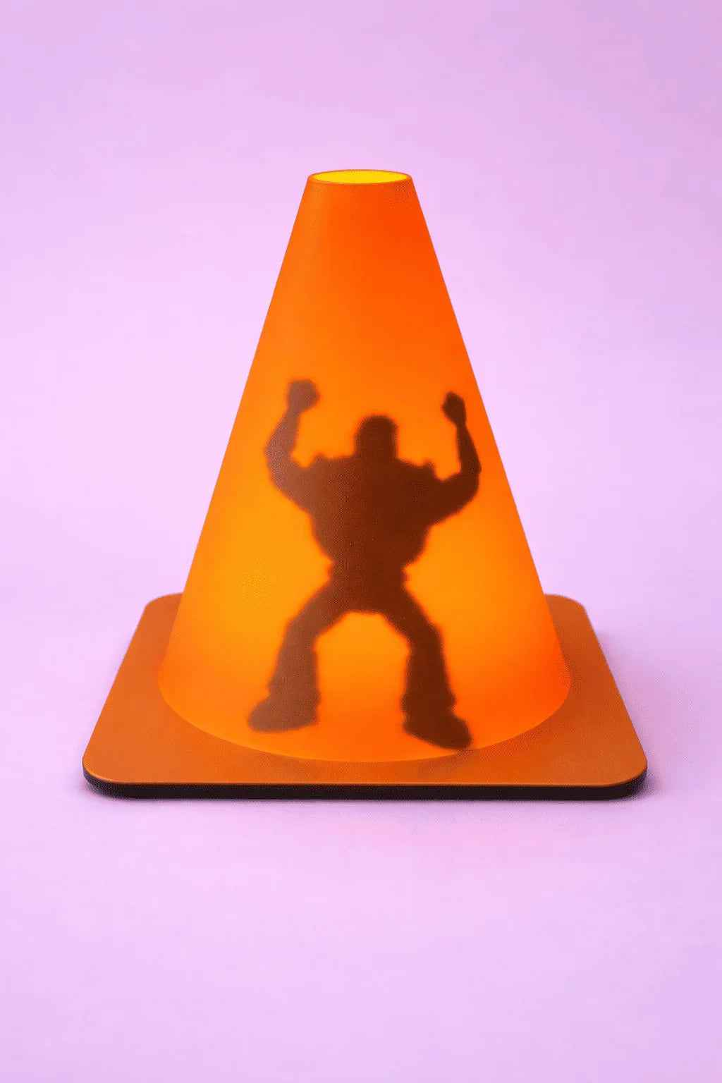 Cono naranja con sombra de figura musculosa en fondo lila, decoración creativa.