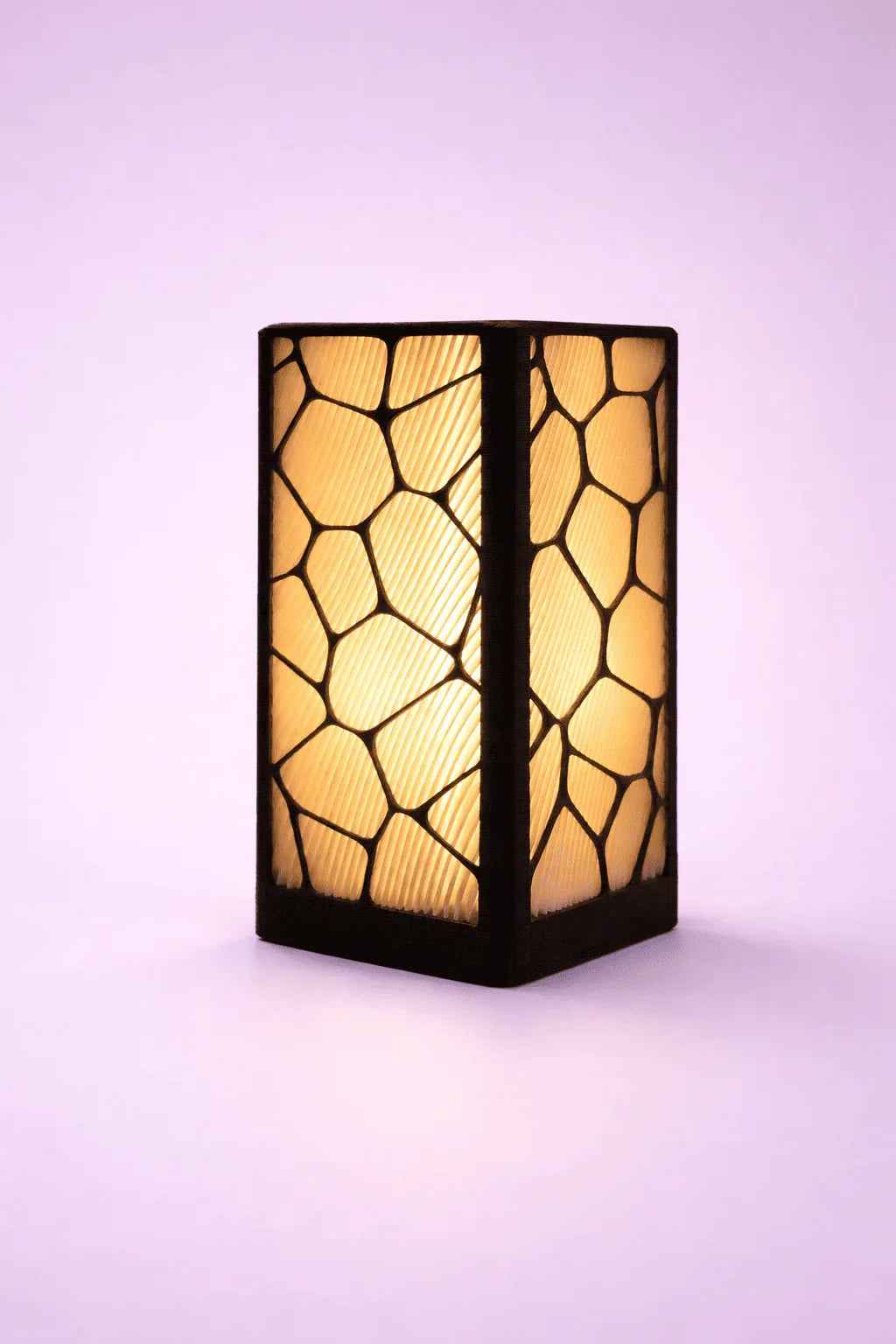 Lámpara decorativa LED de mesa con diseño geométrico y luz cálida sobre fondo morado