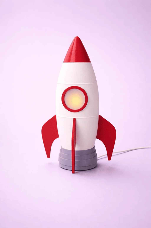 Lámpara cohete blanco y rojo de diseño 3D sobre fondo violeta claro, decoración infantil.