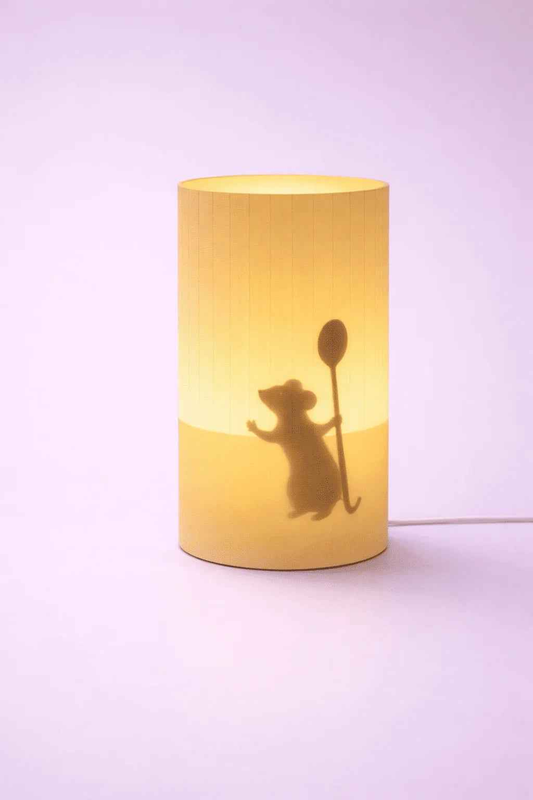 Lámpara decorativa cilíndrica con silueta de ratón sosteniendo cuchara, fondo morado.