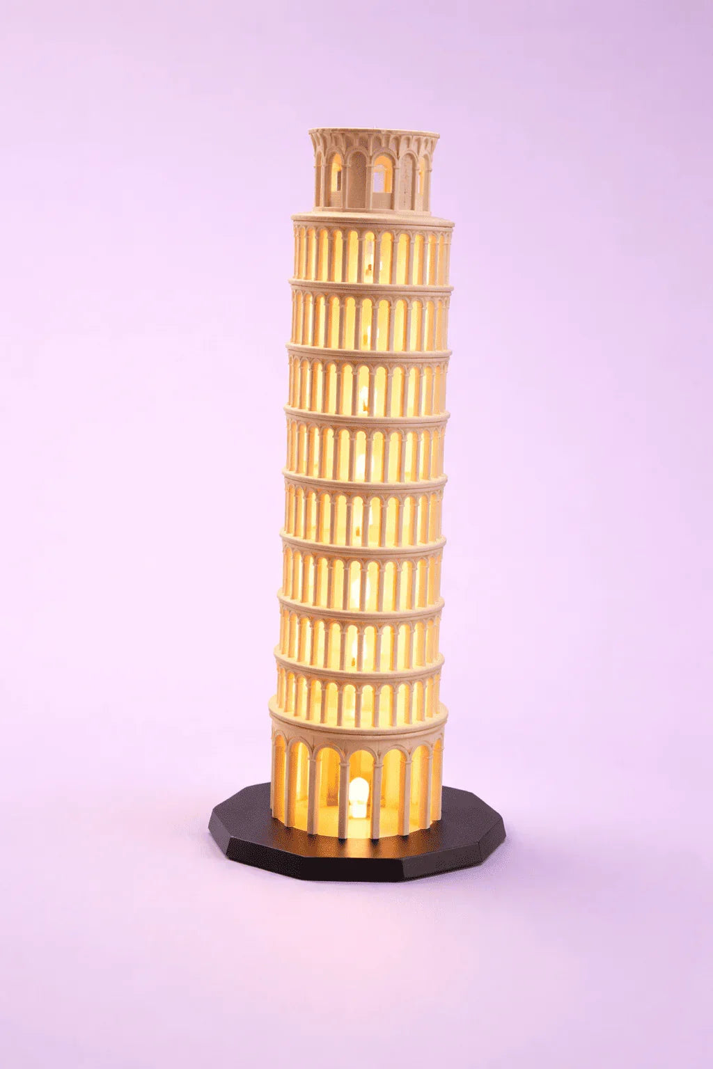 Lámpara decorativa 3D de la Torre de Pisa iluminada con luz cálida sobre fondo morado.