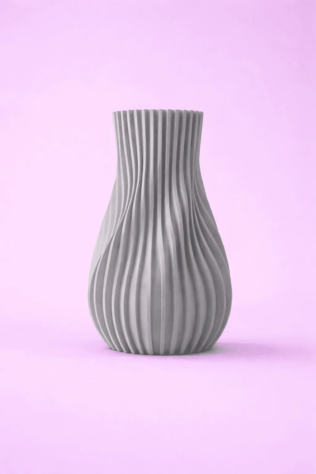 Jarrón gris moderno impreso en 3D con diseño ondulado sobre fondo rosa claro