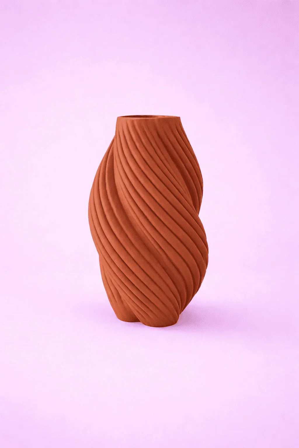 Jarrón marrón de diseño moderno con textura ondulada sobre fondo lila.