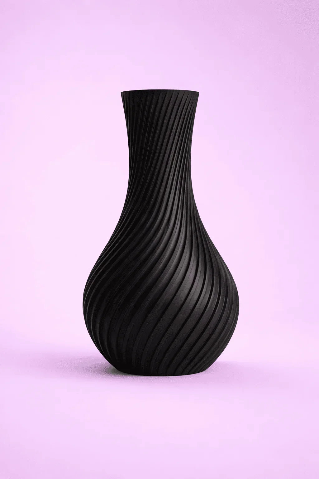 Jarrón negro decorativo con diseño geométrico en espiral sobre fondo rosa claro