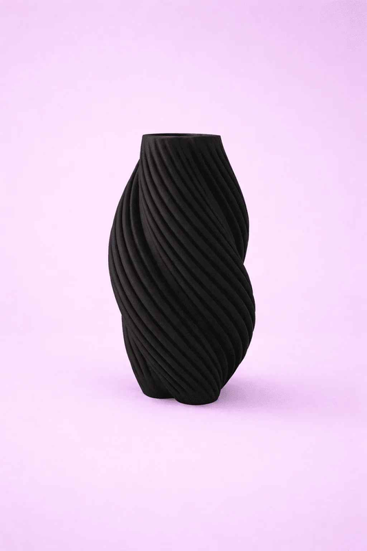 Jarrón negro con diseño espiral moderno sobre fondo lila, decoración minimalista.