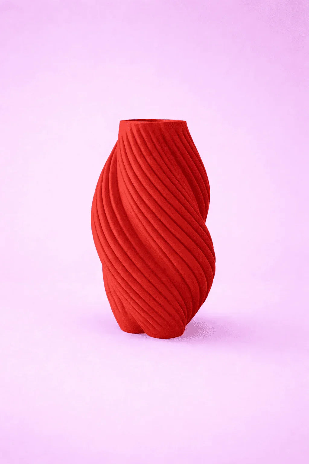 Jarrón moderno rojo de diseño 3D con textura ondulada sobre fondo rosa claro