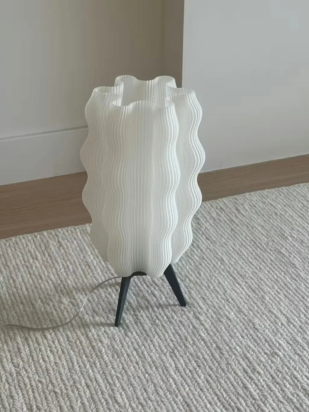 Lámpara de mesa blanca de diseño ondulado con base negra, decoración moderna en interior minimalista