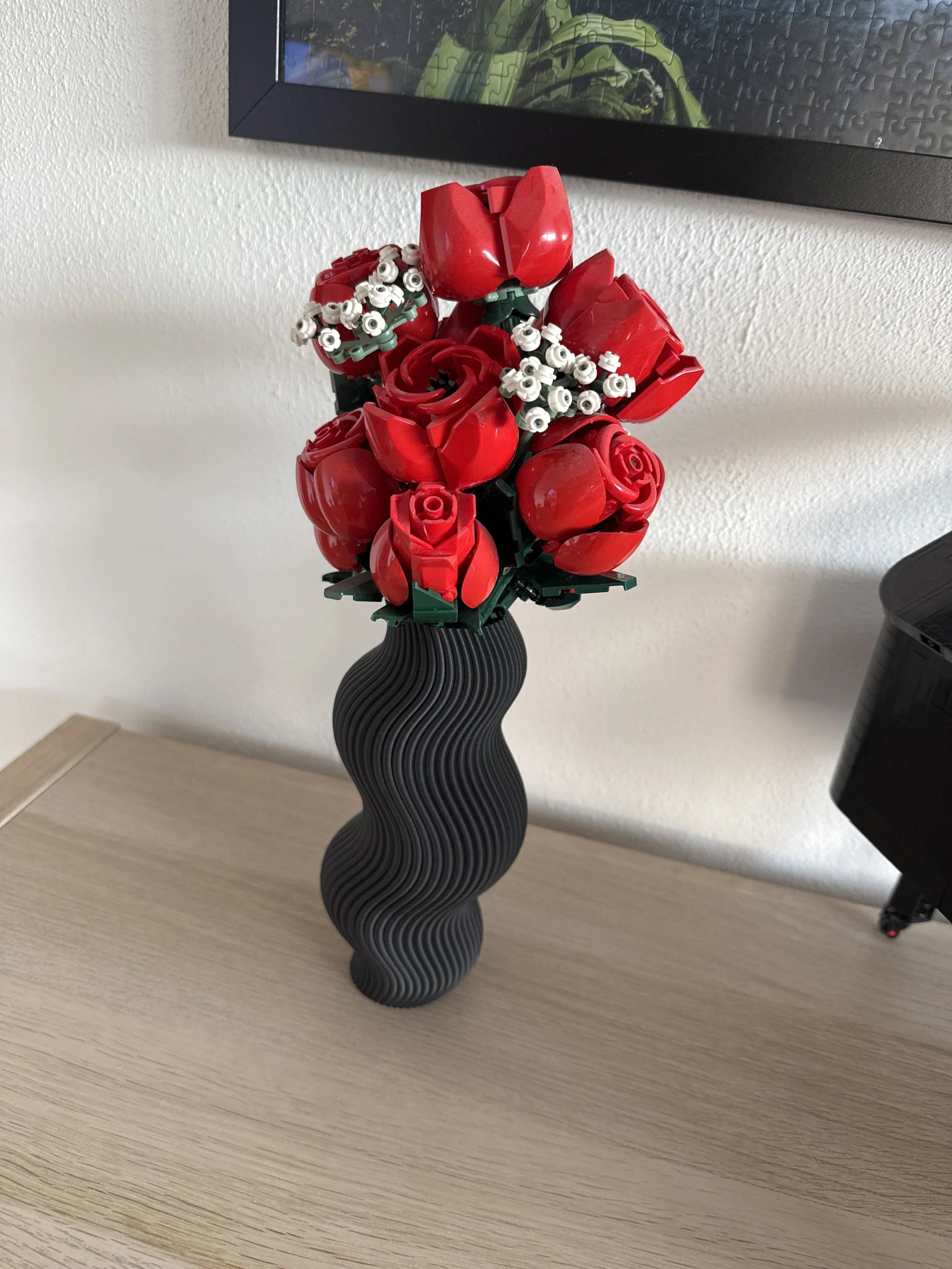 Ramo decorativo de flores rojas y blancas hecho con piezas tipo lego en jarrón moderno negro.